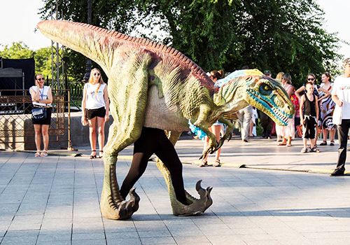 Performer wearing a life-like dinosaur costume at an event