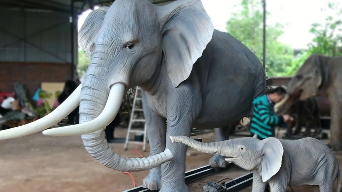 Animatronic African elephant with calf companion in workshop, adult showing head detail and raised trunk