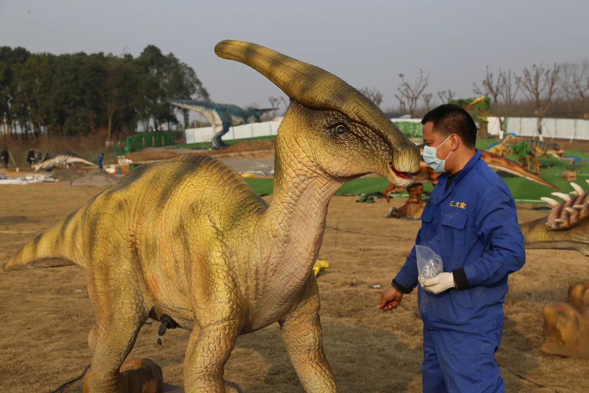 Technician performing routine maintenance on animatronic dinosaur exhibit