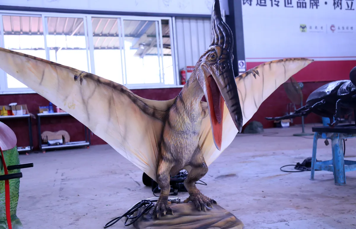 Life-size animatronic pteranodon with swept-back crest standing on a rock base