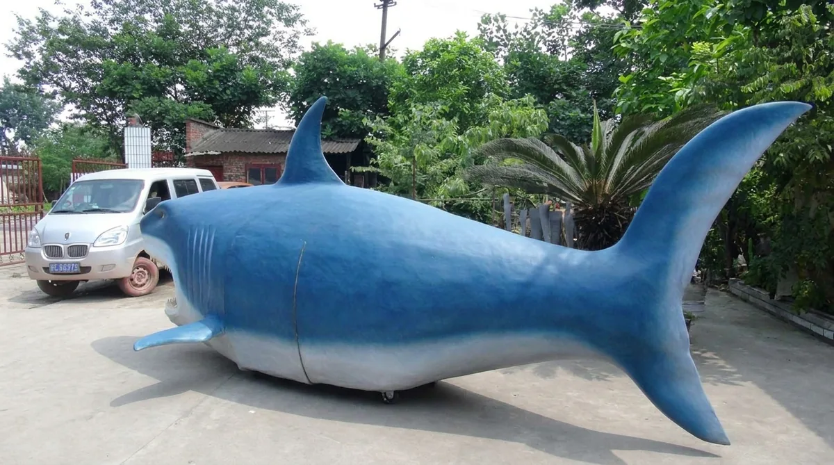 Life-size animatronic great white shark assembled on the factory floor before shipping, shown beside a van for scale