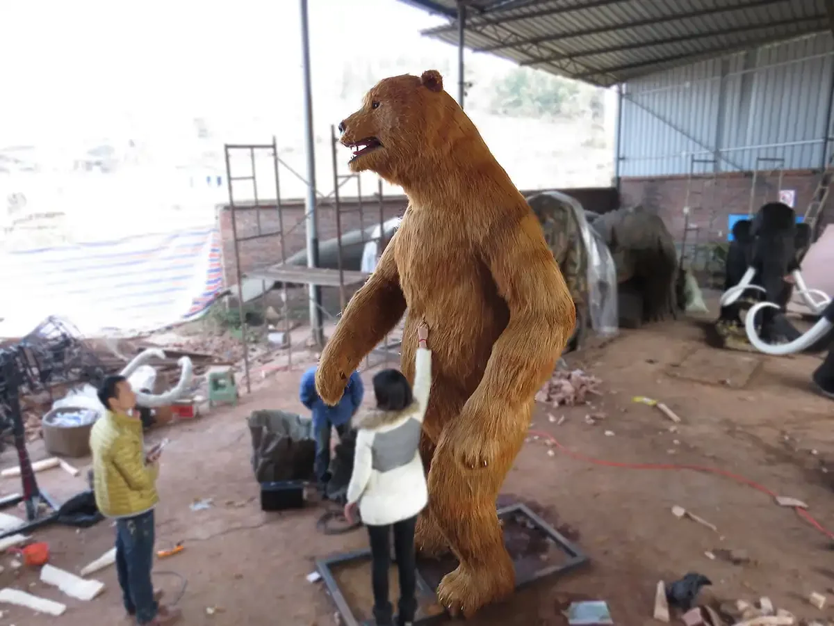 Animatronic cave bear head with hand-pasted fur and open snarling mouth showing sculpted canines