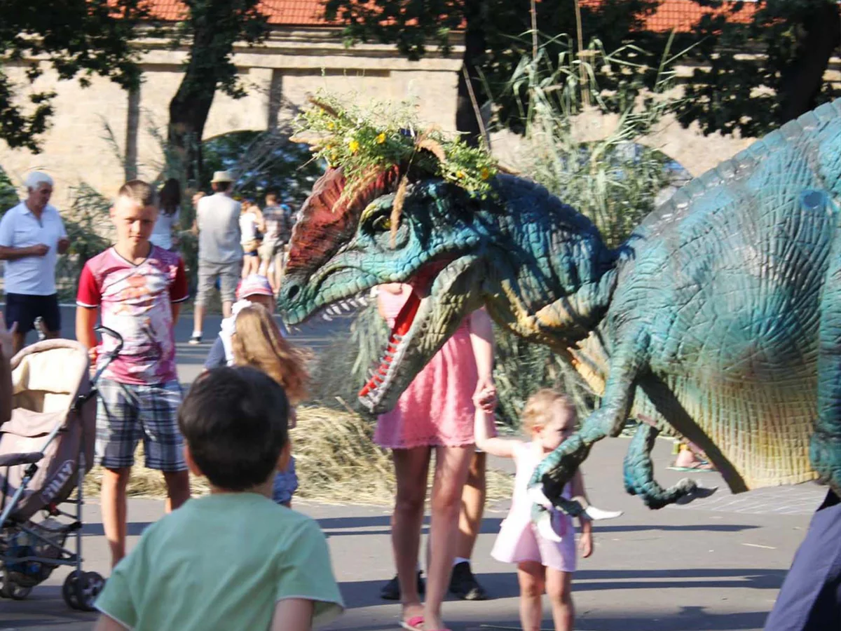 Walking dinosaur costume head close up as visitors gather at an event