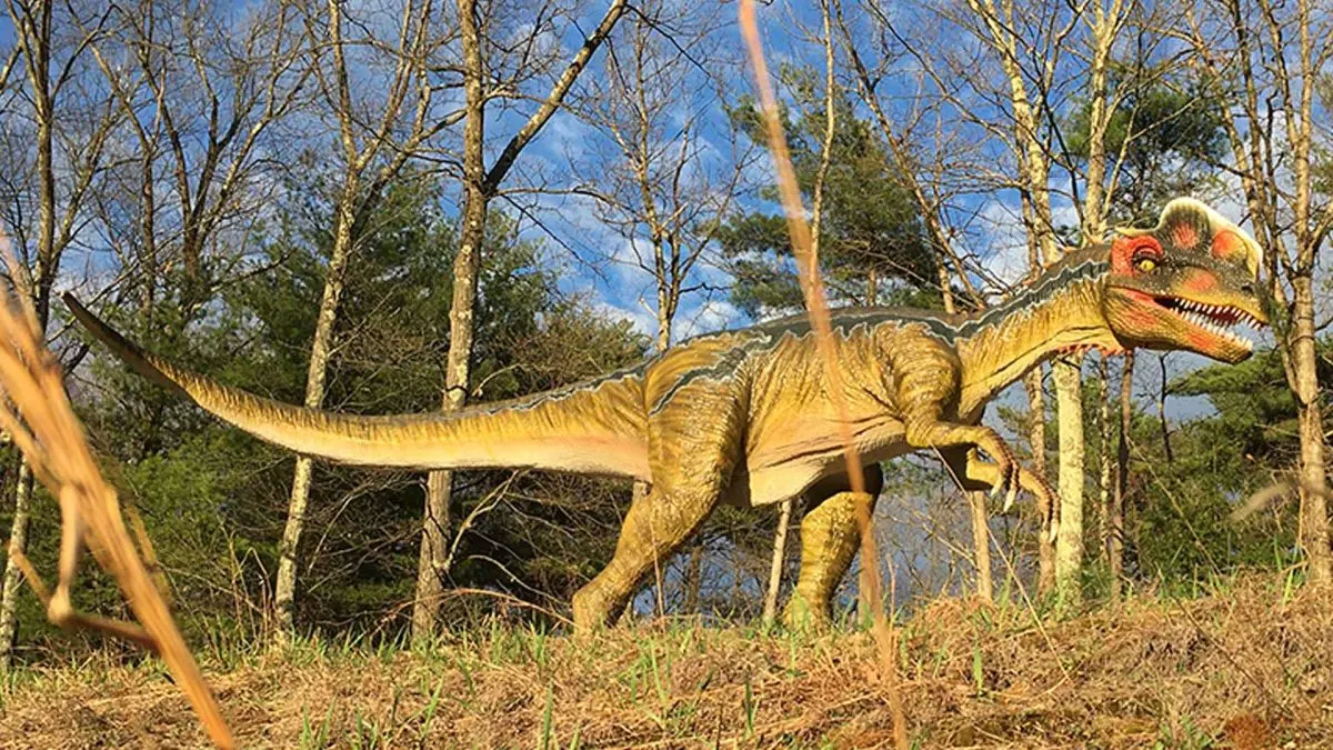 Animatronic Dilophosaurus with twin red crests on outdoor exhibit
