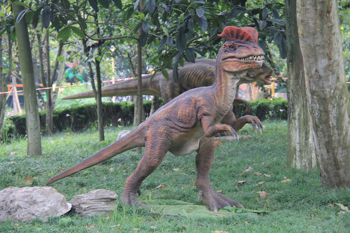 Dilophosaurus ride unit in a stalking stance on a park path