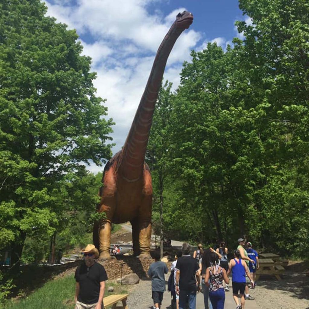 Life-size animatronic Argentinosaurus towering over visitors walking a park path