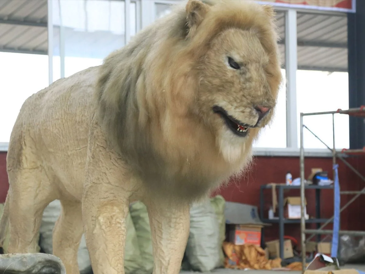 Life-size animatronic lion with detailed mane on outdoor zoo exhibit