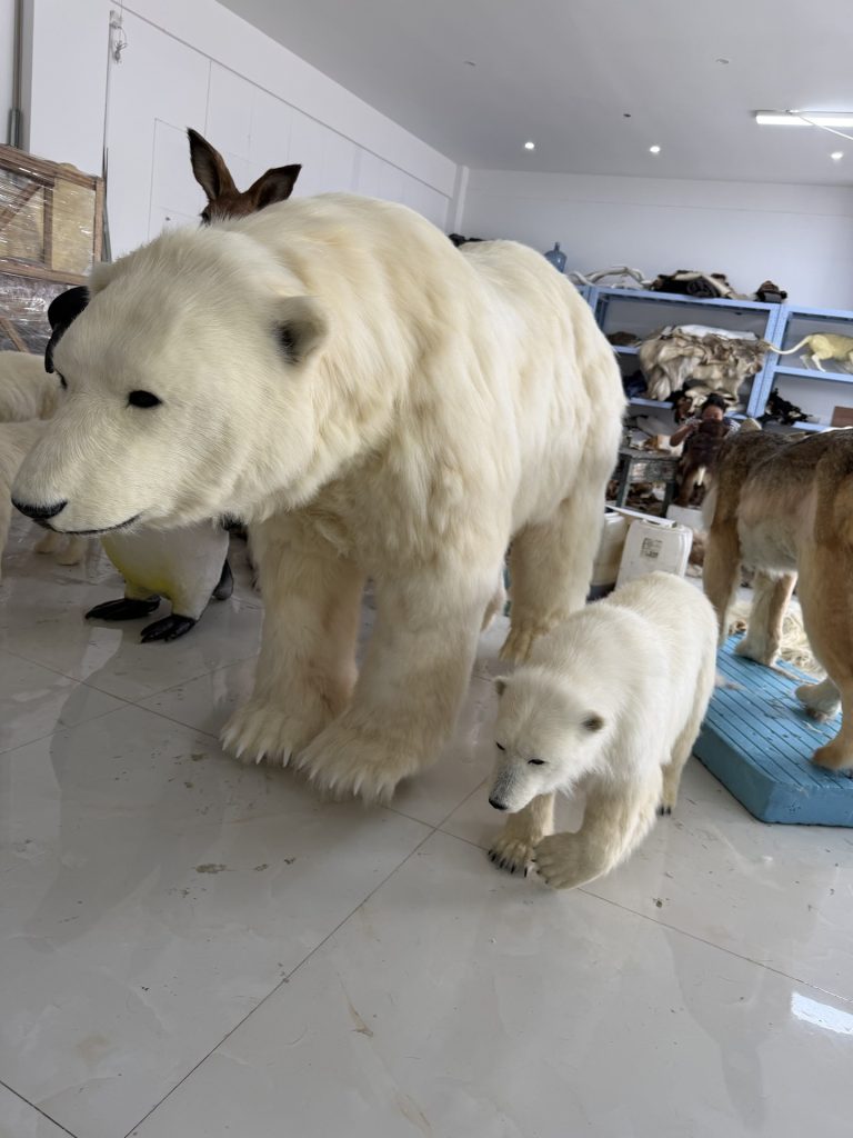 Life-size animatronic polar bear mother with cub standing in an indoor exhibit