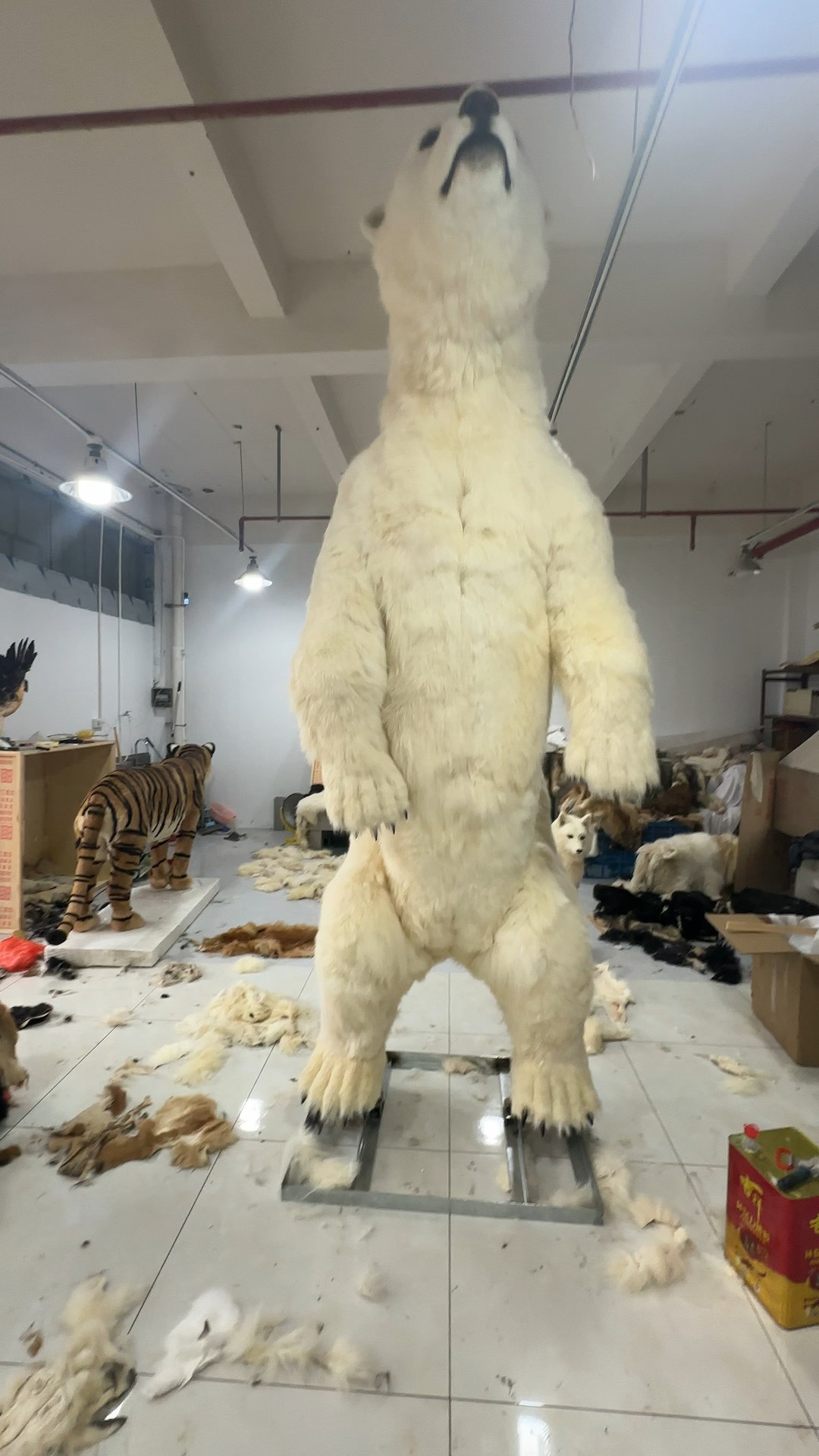 Life-size animatronic polar bear standing upright on a metal base in a workshop
