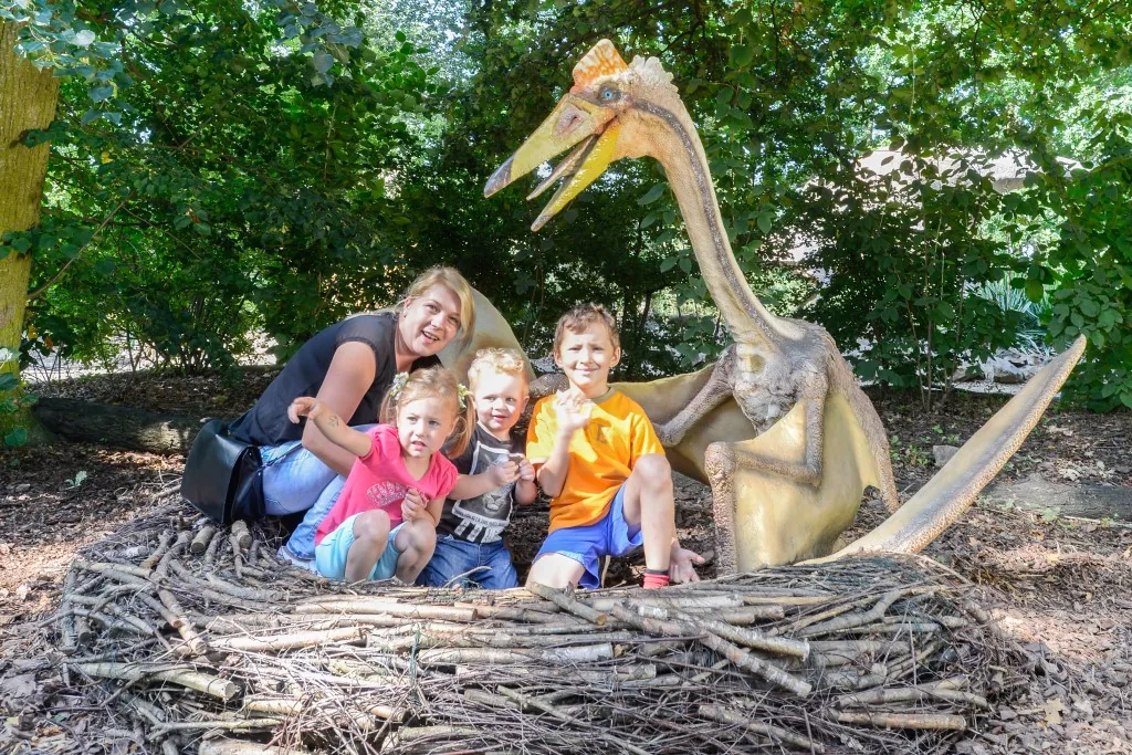 Family posing with an animatronic dinosaur nesting scene