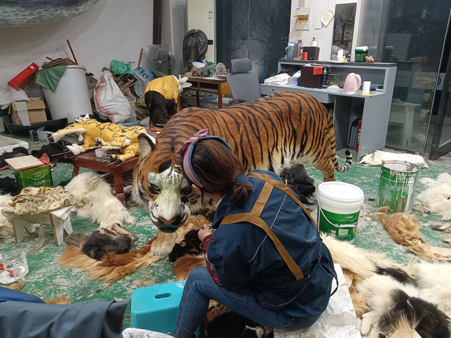 Life-size animatronic tiger being finished by a worker in a manufacturing workshop