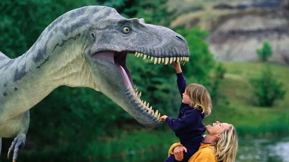 Child reaching up to the lowered head of an animatronic dinosaur